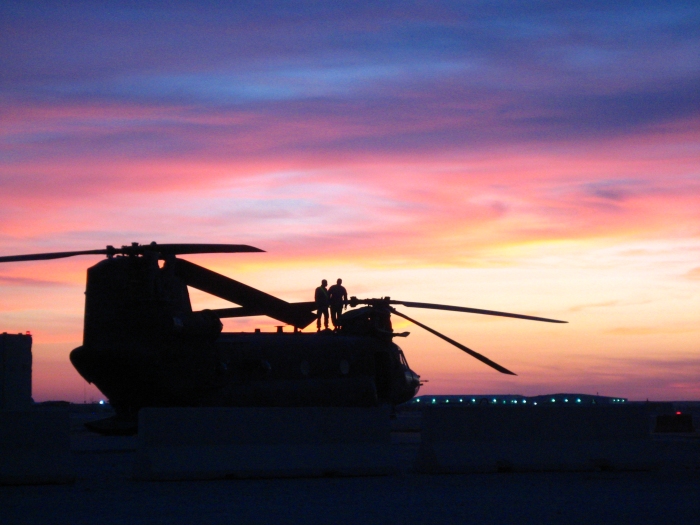 An unknown CH-47D Chinook helicopter preparing to launch on a mission somewhere in the Middle Eastern Theater at sunset.