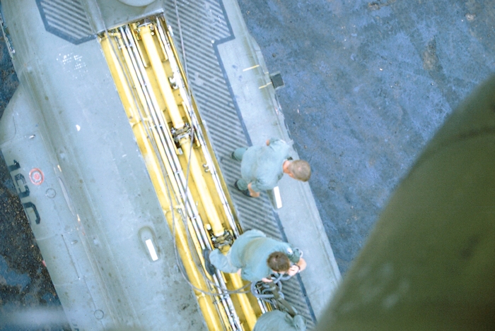 A photograph snapped as 68-15869 hovers close reveals the crew on top of 67-18518 and the exposed drive (sync) shafts and flight control tubes in the tunnel area.