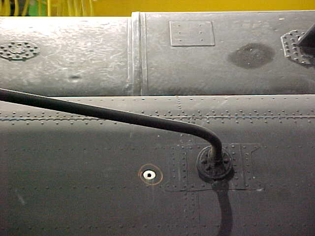 Bullet hole, outside view, left side near aft end of High Frequency (HF) Radio antenna.