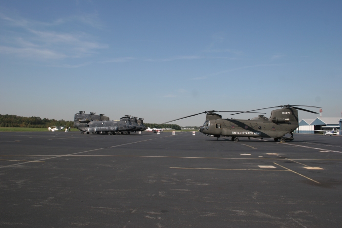 11 October 2006: CH-47F (minus) Chinook helicopter 03-08003 on the ramp at Summit Aviation Airport (KEVY) near Middletown, Delaware. In the background are CH-47D helicopters about to be recycled to facilitate the F model production. Although the F model airframe itself is brand new, all serviceable dynamic parts (those that move), some hydraulic components, and engines from aged D models are used to produce F model helicopters on those aircraft whose tail numbers include the numbers xx-080xx. The xx-087xx tail numbers are all brand new airframes with all brand new components. What is left of the D model airframe is then fed to a shredder and recycled. This recycling is accomplished by Summit Aviation.