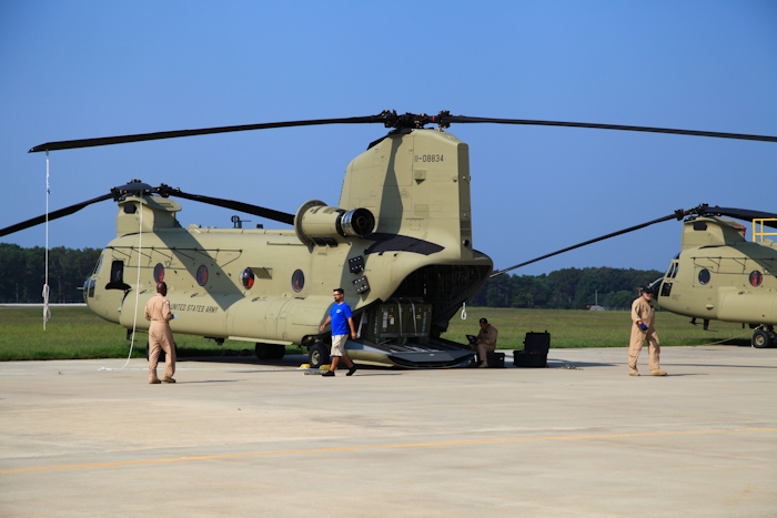 11 September 2013: CH-47F Chinook helicopter 11-08834 rests on the ramp at the Boeing Millville facility, Millville Municipal Airport (KMIV), New Jersey, awaiting movement to the Port of Baltimore for ship transport to the Republic of Korea. On the left is New Equipment Training Team Standardization Pilot Ahmad Upshaw, sitting Is Standardization Instructor Noel Cabias and walking off to the right is Standardization Instructor Bill Cagle. The fellow in the blue shirt is unknown.
