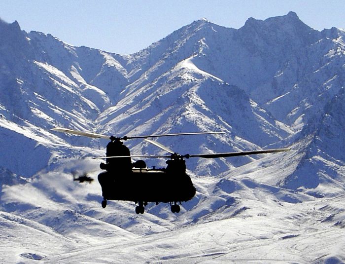 A CH-47D Chinook helicopter, escorted by an AH-64 Apache, flies through a snow covered mountain range in Afghanistan. It carries vital cargo and personnel to a Coalition facility. U.S. Army aviation assets are playing a key role in the "Global War Against Terrorism".