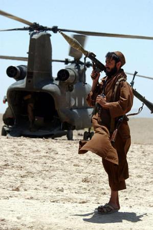 Local Afghan gunmen holding rocket propelled grenades (RPG) guard an American Chinook helicopter.