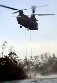 An Army National Guard CH-47D Chinook helicopter drops 15,000-pound bags of sand into a levee that gave way in New Orleans.