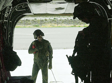 Staff Sgt. Ken McLaughlin of Company D, 113th Aviation Regiment watches as SFC Brian Soule puts on his flight vest before their training exercise aboard a Chinook helicopter Sunday at the Reno-Stead Airport.