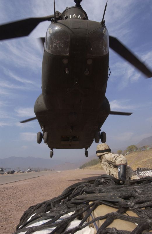 A soldier waits for hook-up as a U.S. Army CH-47D Chinook helicopter approaches a cargo net full of humanitarian relief supplies that will be sling loaded from Muzaffarabad, Pakistan.