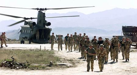 Royal Marine Commandos walk past a British HC Mark II Chinook helicopter.