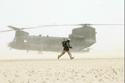 A British soldier of 51 Squadron, Royal Air Force, runs past a Chinook helicopter.