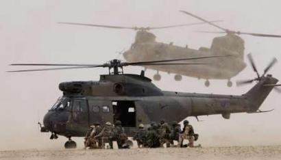 British Royal Air Force Regiment troops from 51 Squadron prepare to board a Puma helicopter as a Chinook takes off.